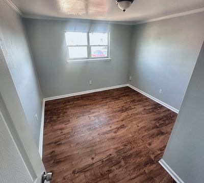 Bedroom with wood-look floor and window in a 2-bedroom Metairie home
