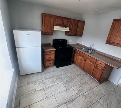 Kitchen with wood cabinets and white refrigerator in a 2-bedroom Metairie home
