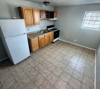 Kitchen with wood cabinets and white refrigerator in a 2-bedroom Metairie home